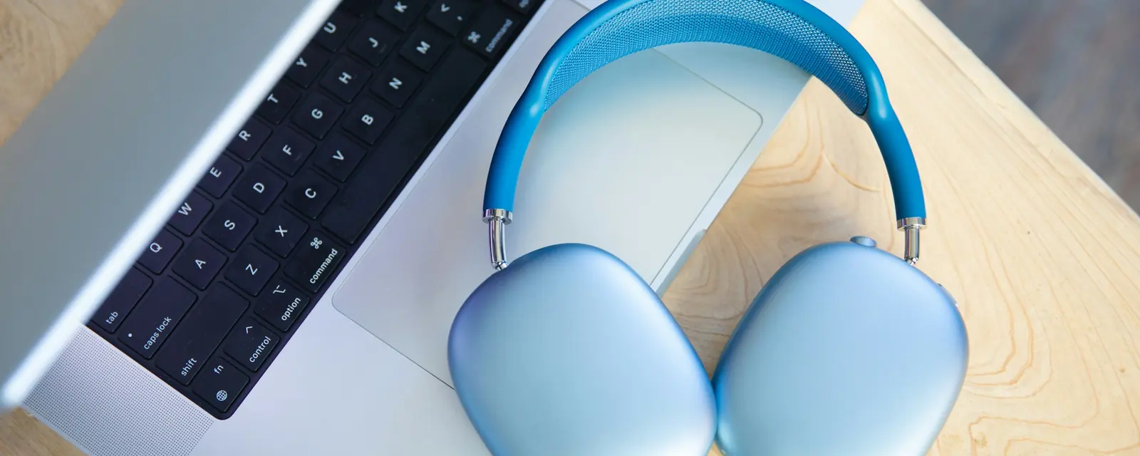 Headphones resting on a laptop on a wooden desk